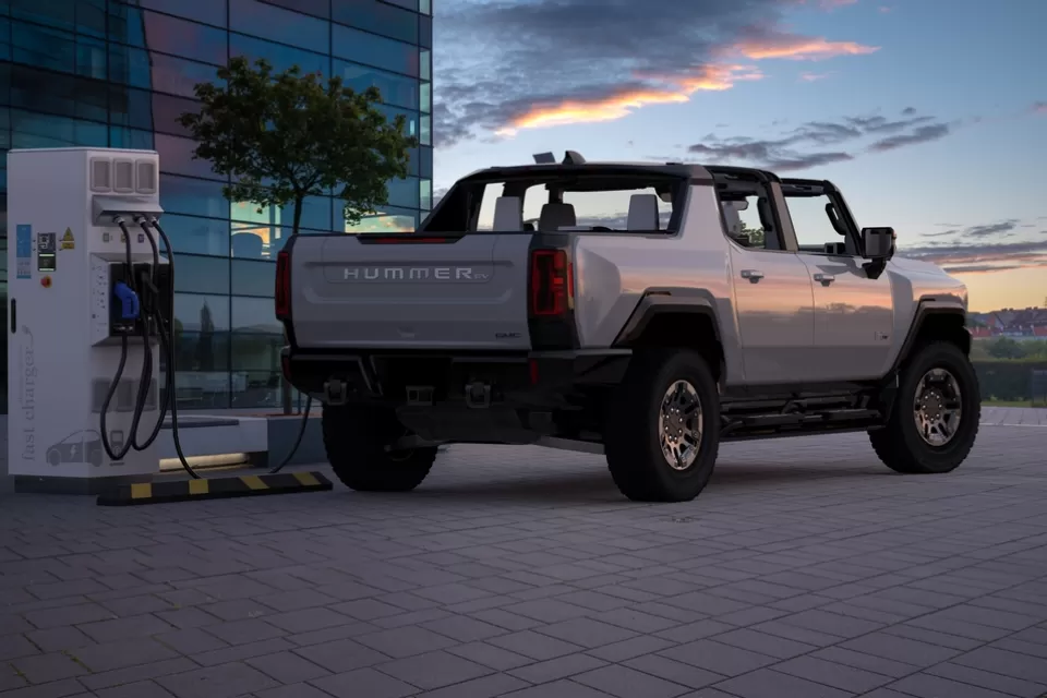 Rendering of grey convertible electric Hummer charging at a charging station against a sunset sky